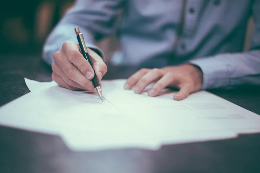 Hands writing on a contract